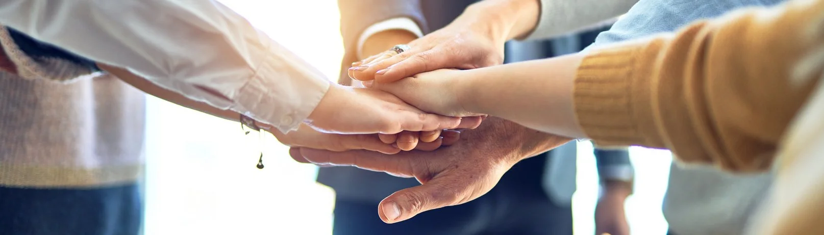 Group of business workers standing with hands together at the of